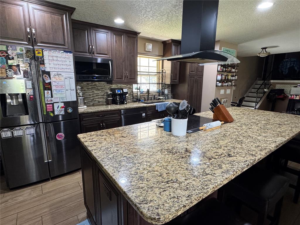 A kitchen features dark wood cabinets, granite countertops, a large island, and stainless steel appliances — 513 OAKCREST STREET, ALTAMONTE SPRINGS, FL