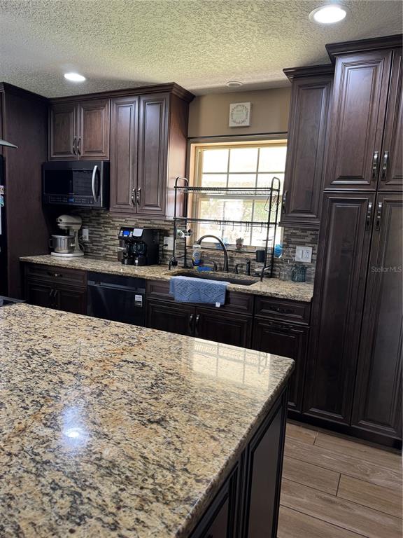 A kitchen features dark wood cabinets, granite countertops, and a stainless steel sink — 513 OAKCREST STREET, ALTAMONTE SPRINGS, FL