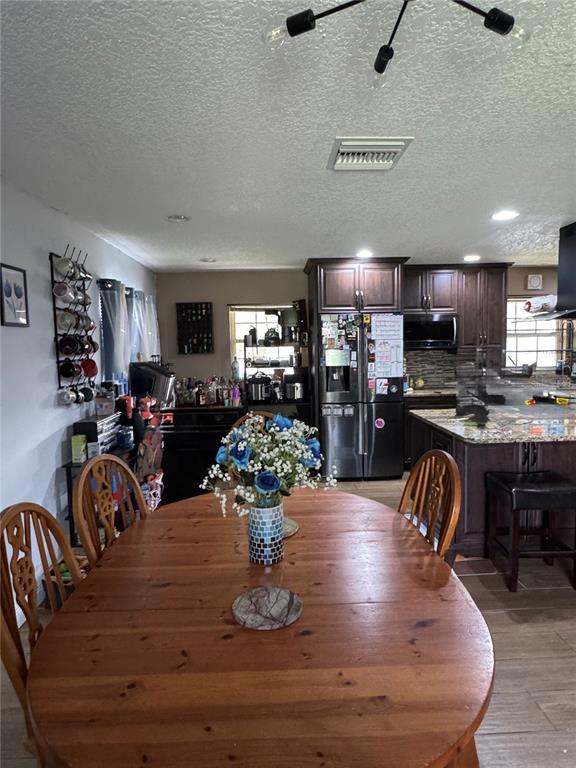 A dining area with a wooden table leads into an open kitchen with dark cabinetry — 513 OAKCREST STREET, ALTAMONTE SPRINGS, FL