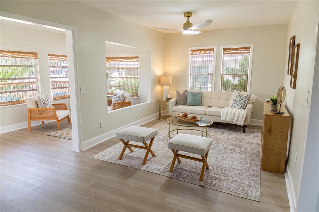 A living room features a beige sofa, two ottomans, a coffee table, and light flooring — 13148 3RD STREET E, ST PETERSBURG, FL
