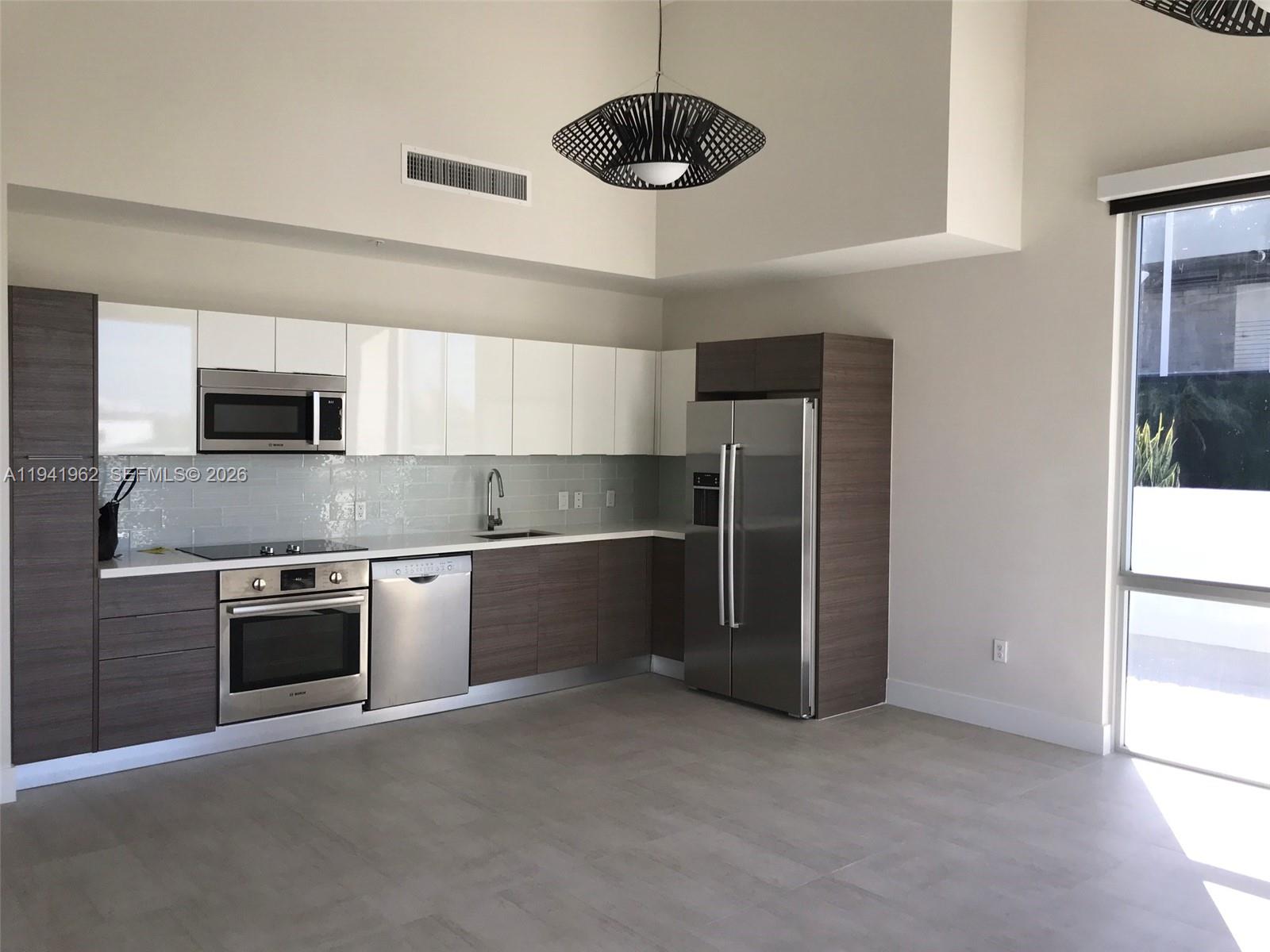 A modern kitchen features two-toned cabinetry, stainless steel appliances, and a light gray tile floor — 1010 SW 2nd Ave # 506, Miami FL 33130, MIAMI, FL