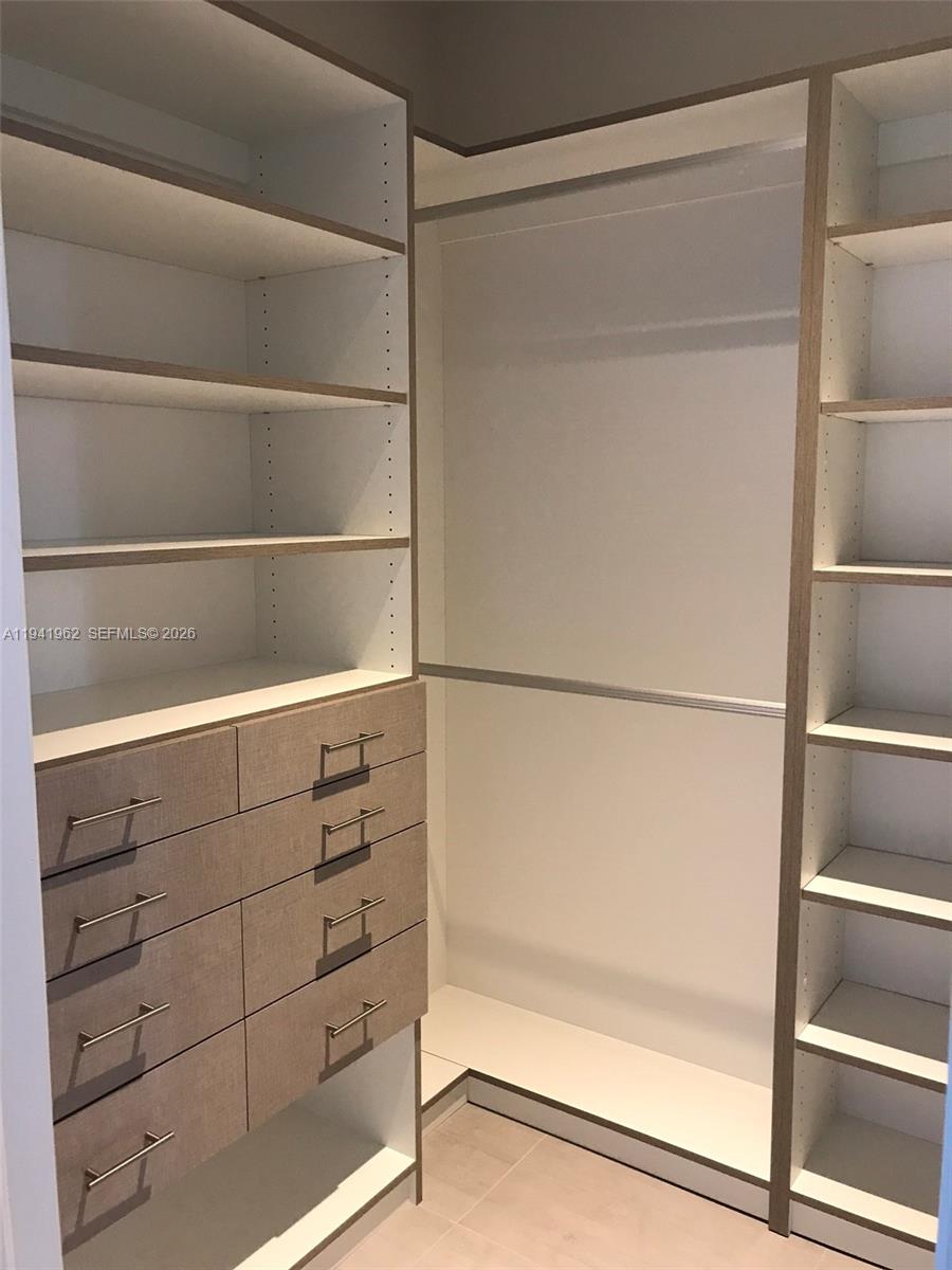 A walk-in closet features white shelving, light wood-textured drawers, and a hanging rod — 1010 SW 2nd Ave # 506, Miami FL 33130, MIAMI, FL