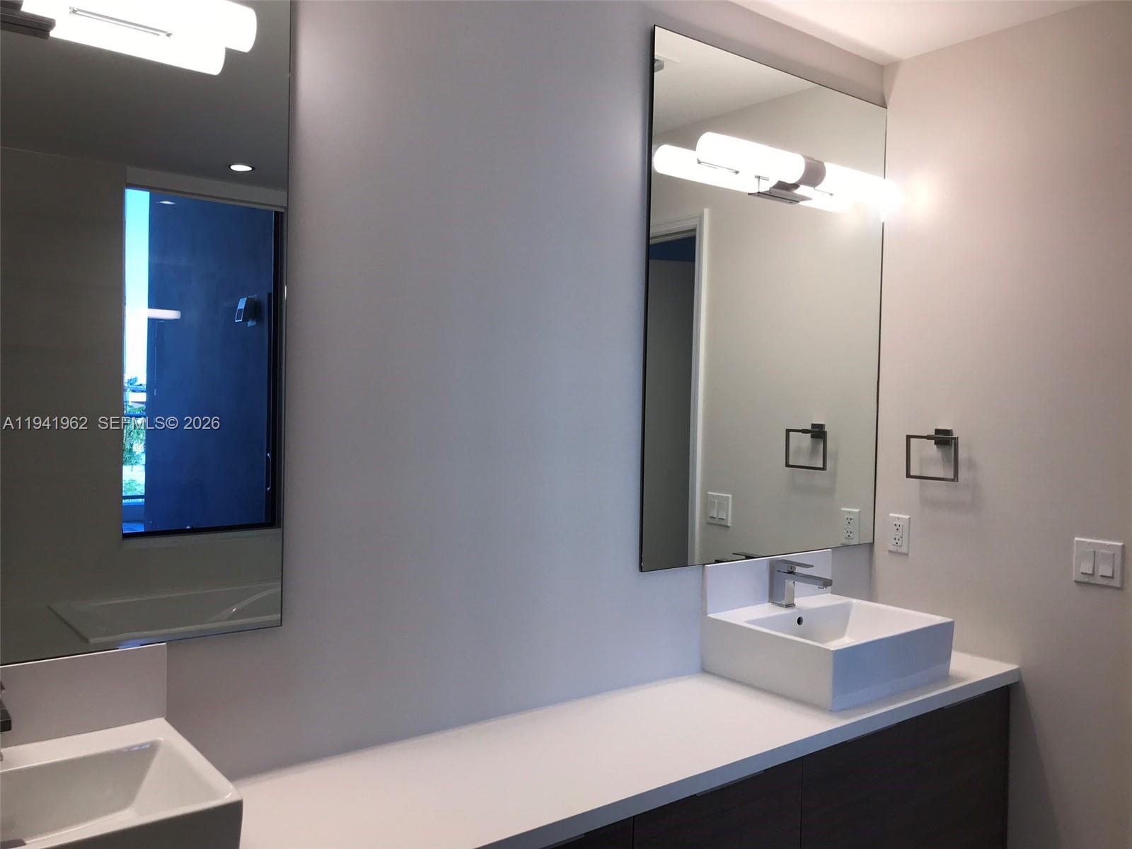 A modern bathroom features a double vanity with vessel sinks, large mirrors, and wall lighting — 1010 SW 2nd Ave # 506, Miami FL 33130, MIAMI, FL