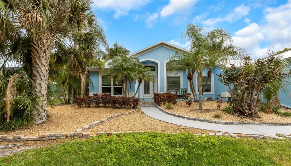 A light blue single-story house features a curved walkway, palm trees, and gravel landscaping — 424 ISLAND CAY WAY, APOLLO BEACH, FL
