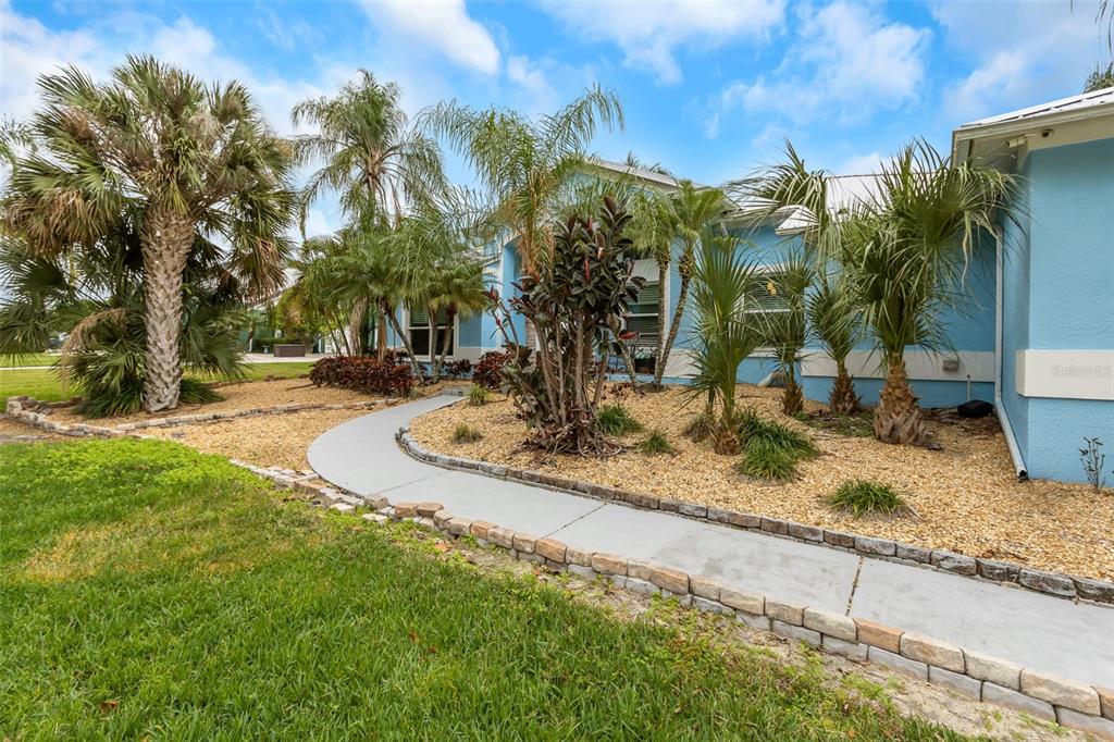 A light blue house exterior features a curved concrete walkway through a landscaped rock garden — 424 ISLAND CAY WAY, APOLLO BEACH, FL
