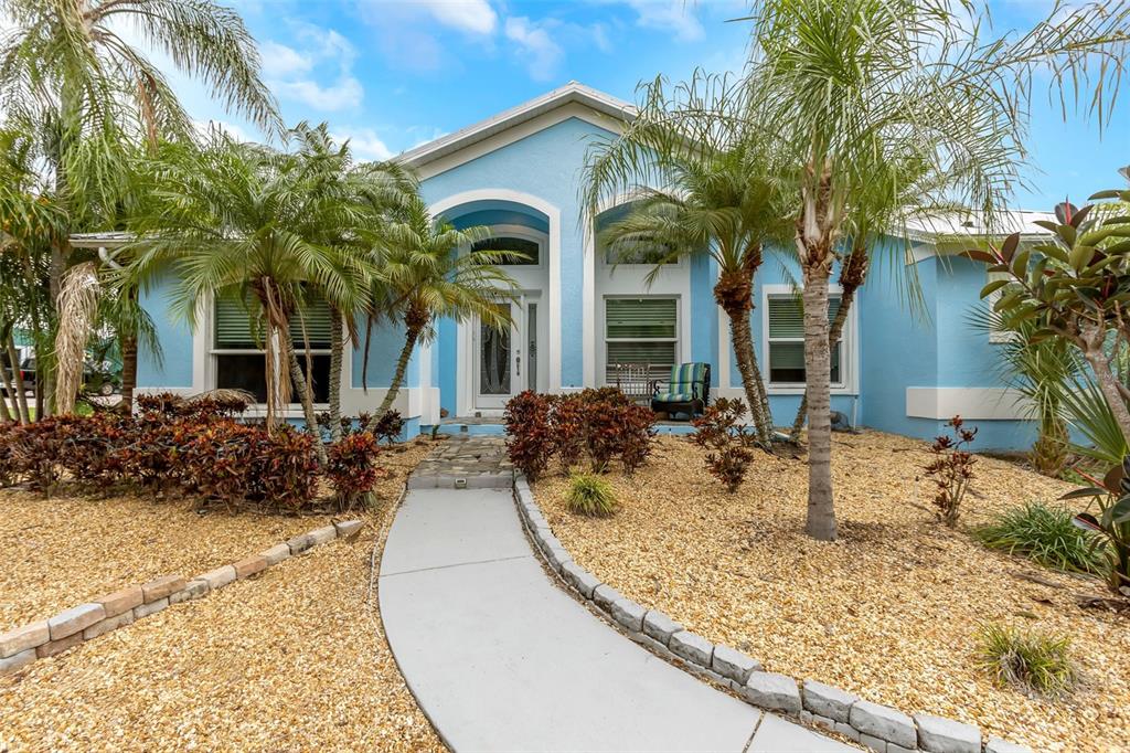 A light blue single-story house with a stone walkway, palm trees, and gravel landscaping — 424 ISLAND CAY WAY, APOLLO BEACH, FL