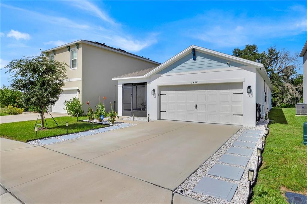 A single-story house with a white garage, light blue gable, and a paved driveway — 2497 RIBBON FALL AVENUE, DAVENPORT, FL