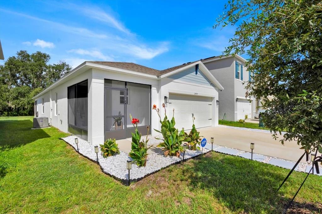 A single-story house with a white exterior, a screened-in porch, and a two-car garage — 2497 RIBBON FALL AVENUE, DAVENPORT, FL