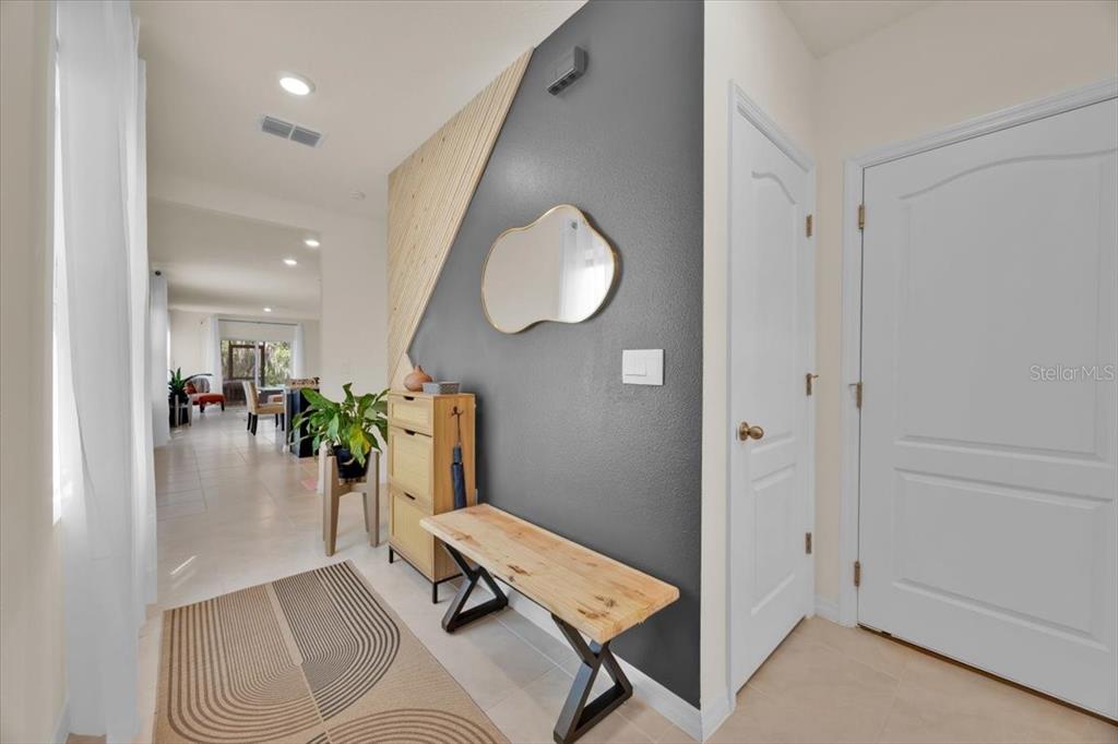 An entryway features a wood-slat accent wall, a bench, a mirror, and a tile floor — 2497 RIBBON FALL AVENUE, DAVENPORT, FL