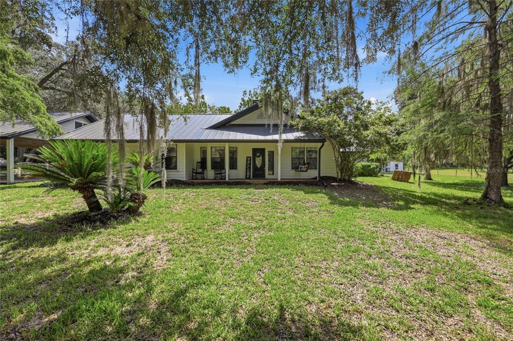 A single-story house with a metal roof and a front porch sits on a lawn — 22929 E COUNTY ROAD 1474, HAWTHORNE, FL