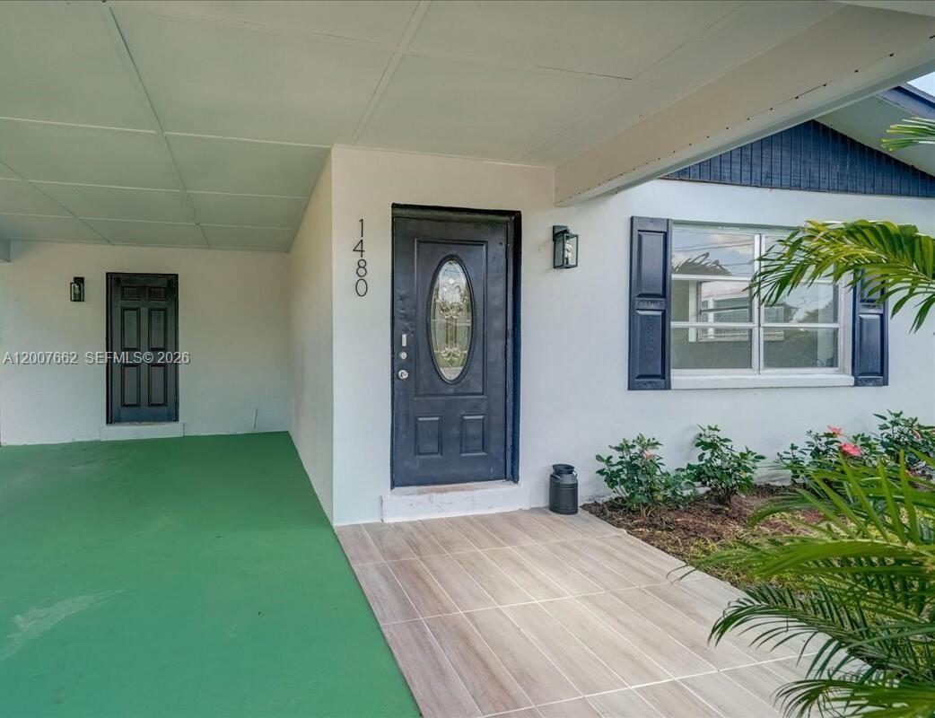The exterior of a house features a green porch, a dark front door, and windows — 1480 W 36th St, Riviera Beach FL 33404, RIVIERA BEACH, FL