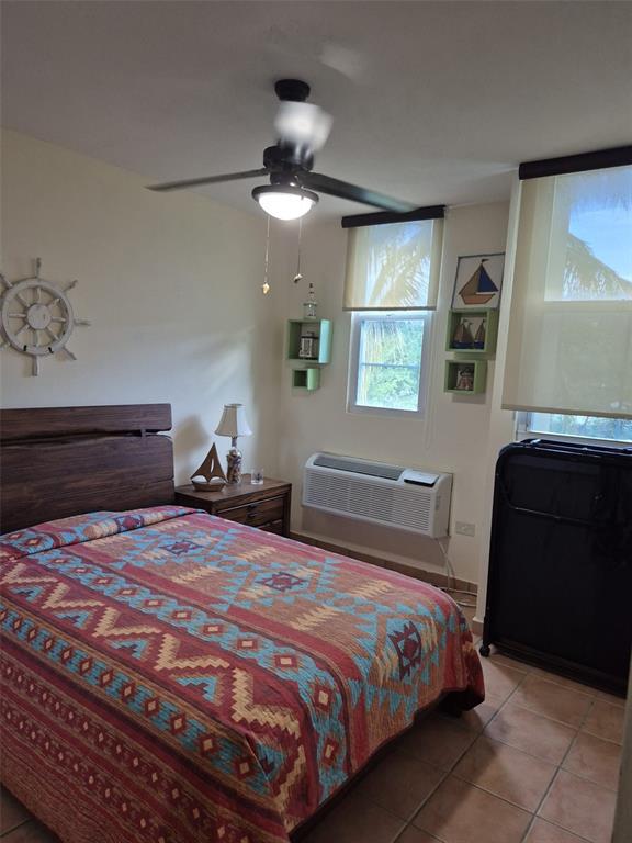 A bedroom features a wooden headboard, a patterned quilt, a ceiling fan, and nautical decor — I-205 VILLAS DEL MAR RESORT UNIT I-205, LOIZA, PR