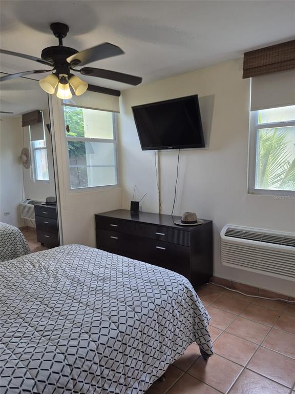 A bedroom features a bed, a dresser with a television, and a ceiling fan — I-205 VILLAS DEL MAR RESORT UNIT I-205, LOIZA, PR