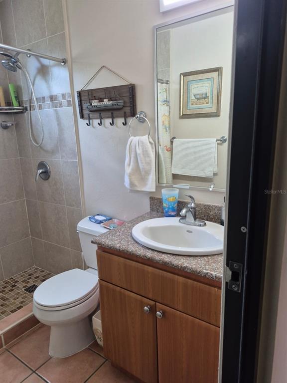 A bathroom features a wood vanity, a white toilet, and a tiled walk-in shower — I-205 VILLAS DEL MAR RESORT UNIT I-205, LOIZA, PR