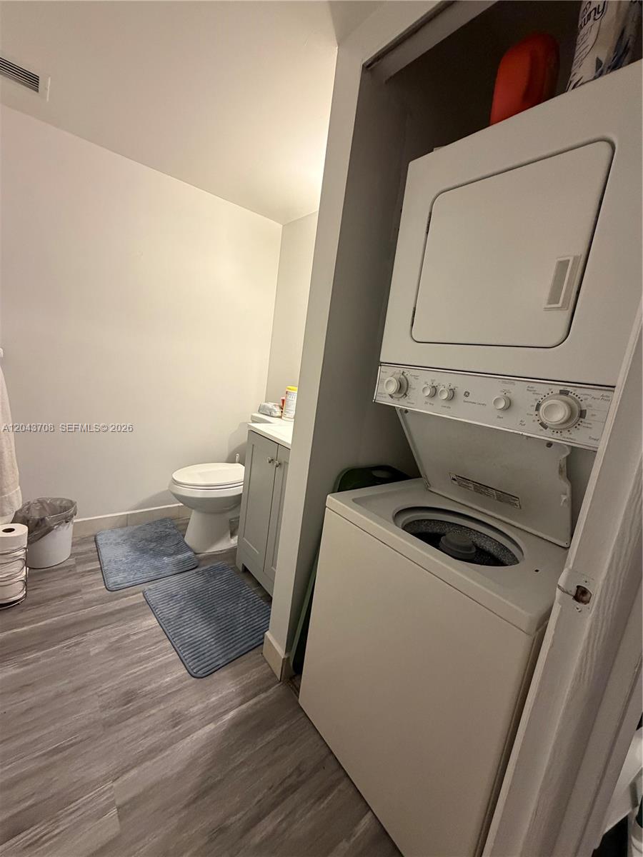 A laundry closet with a stacked washer and dryer sits next to a small bathroom — 4174 Inverrary Dr # 408, Lauderhill FL 33319, LAUDERHILL, FL