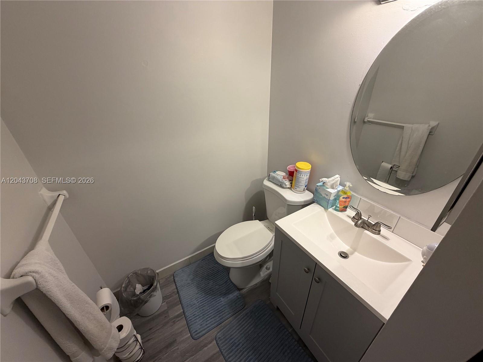 A small bathroom features a white toilet, a grey vanity with a sink, and a mirror — 4174 Inverrary Dr # 408, Lauderhill FL 33319, LAUDERHILL, FL