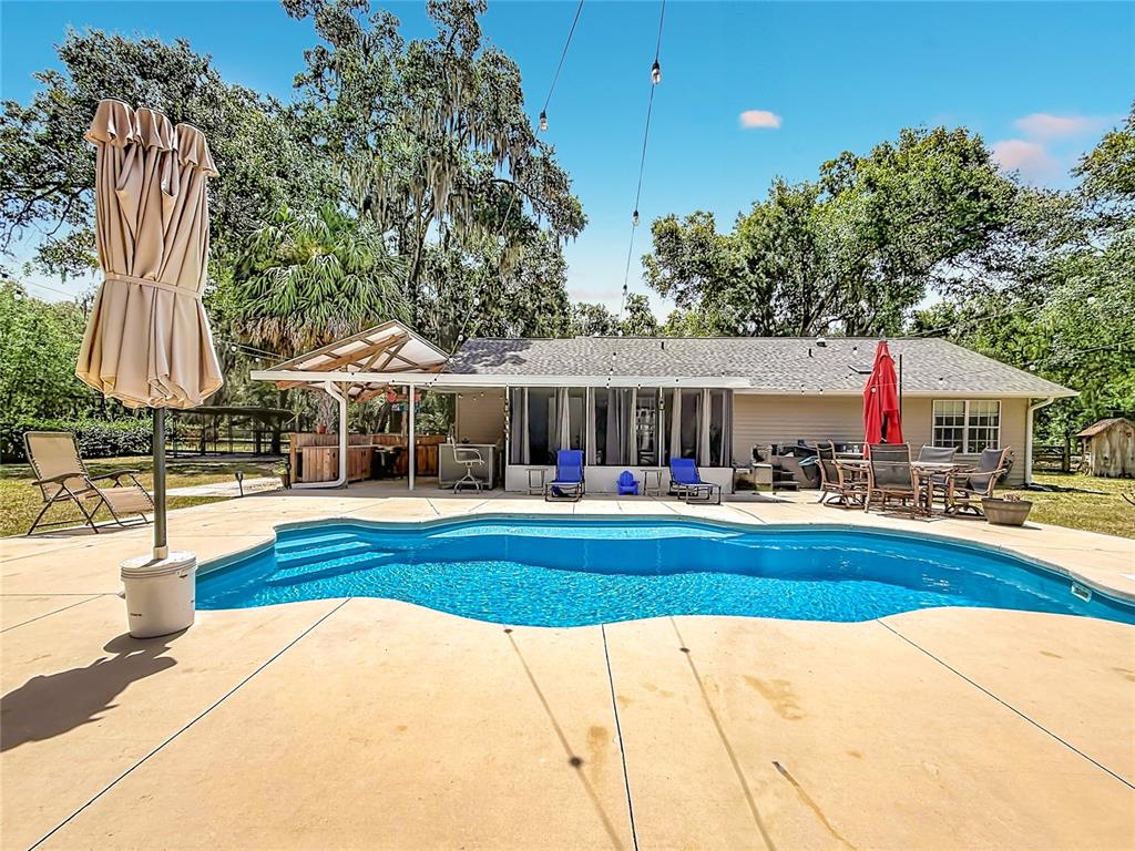 A backyard features a swimming pool, a patio with outdoor furniture, and a house exterior — 12290 SE 141ST AVENUE ROAD, OCKLAWAHA, FL