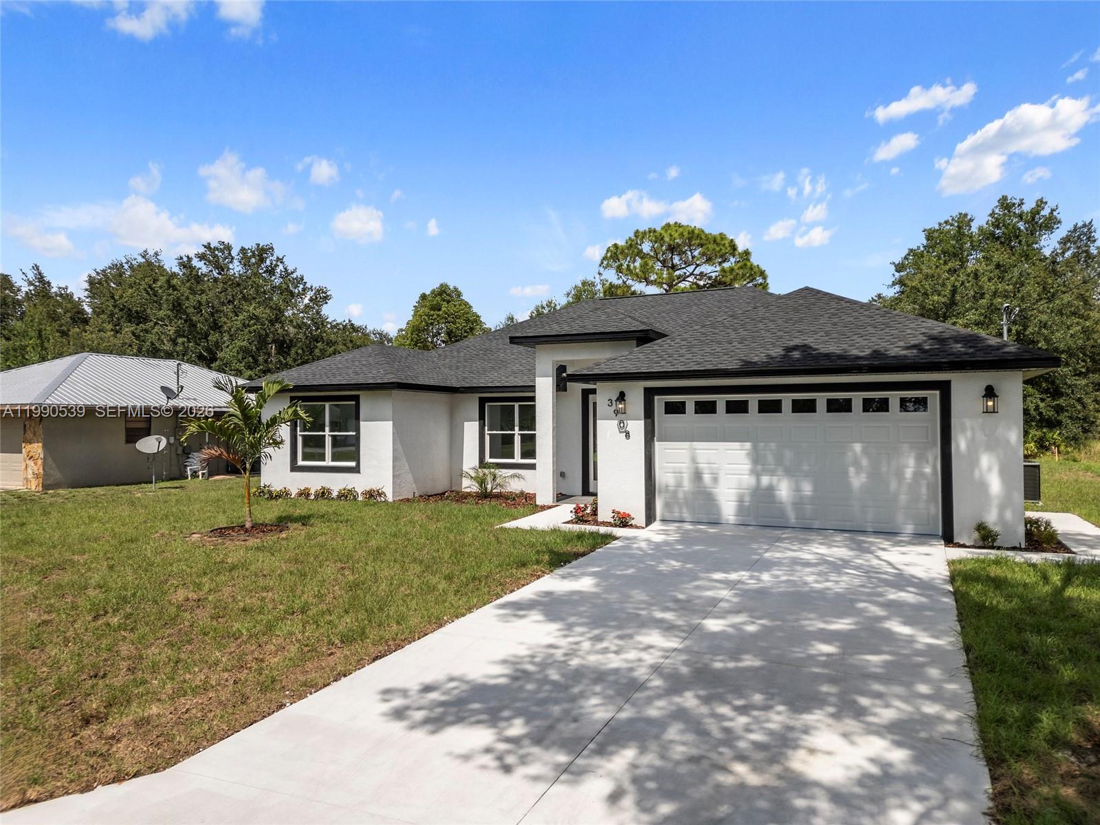 A white single-story house with a black roof and a concrete driveway sits on grass — 3908 Garienda Ave, Sebring FL 33872, SEBRING, FL
