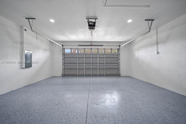 A clean, empty two-car garage with a gray epoxy floor and white walls — 3908 Garienda Ave, Sebring FL 33872, SEBRING, FL