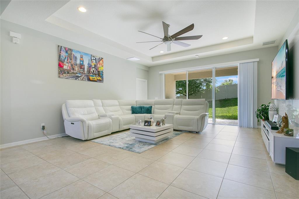 A living room features a white sectional sofa, a coffee table, and a large television — 4918 WILDWOOD POINTE ROAD, WINTER GARDEN, FL