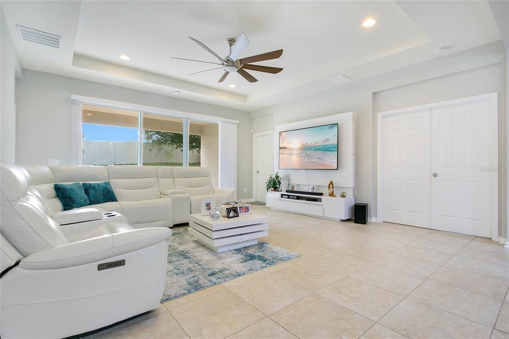 A bright living room features a white sectional sofa, a coffee table, and a television — 4918 WILDWOOD POINTE ROAD, WINTER GARDEN, FL