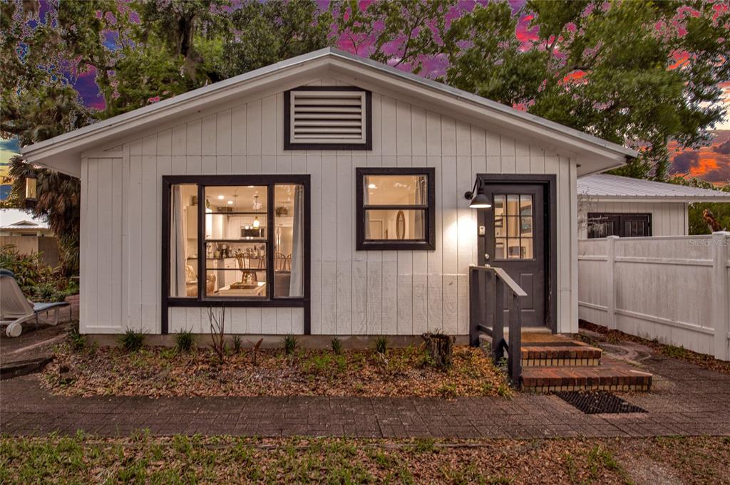 A small white cottage with black trim, a large window, and a brick-stepped entrance — 801 CANAL STREET, NEW SMYRNA BEACH, FL