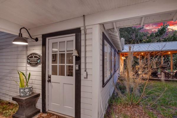 A white exterior door with a glass pane sits beside a wall-mounted lamp and sign — 801 CANAL STREET, NEW SMYRNA BEACH, FL