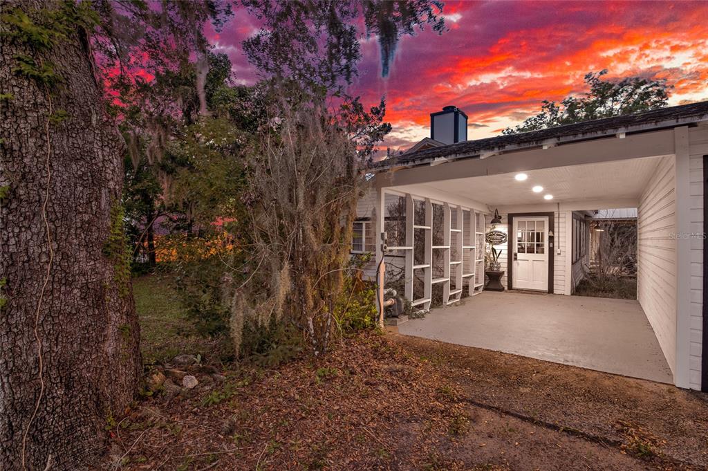 A covered carport leads to a white door on the side of a house at sunset — 801 CANAL STREET, NEW SMYRNA BEACH, FL