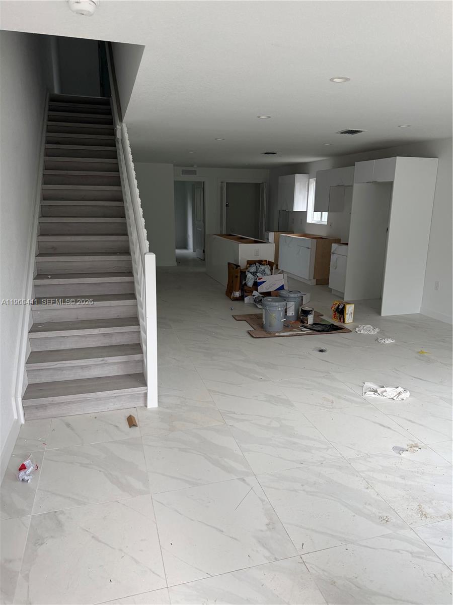 An unfinished open-concept kitchen and living area features white tile floors and a staircase — 7823 NW 5th Ave, Miami FL 33150, MIAMI, FL