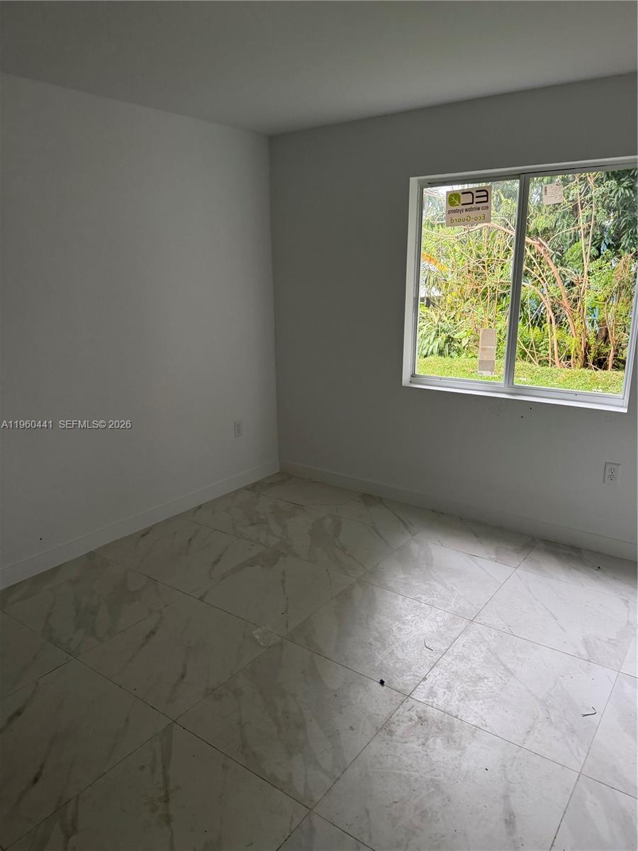 An empty bedroom features white walls, light-colored marble-style tile flooring, and a single window — 7823 NW 5th Ave, Miami FL 33150, MIAMI, FL