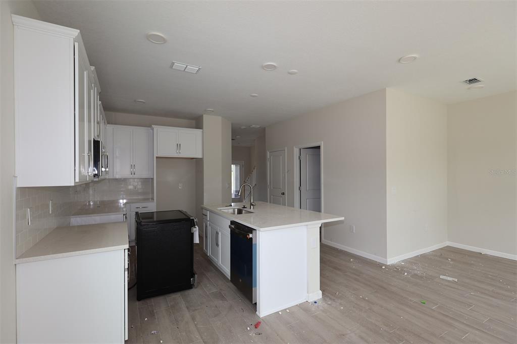 A modern kitchen features white cabinets, a central island, and light-colored wood-look tile flooring — 1429 HYDE STREET, ST CLOUD, FL