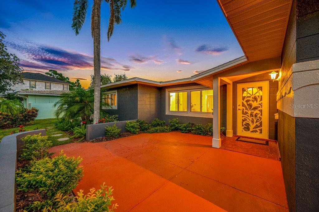 A house exterior features a bright orange driveway, a covered entryway, and a decorative glass door — 328 BAYVIEW DRIVE NE, ST PETERSBURG, FL