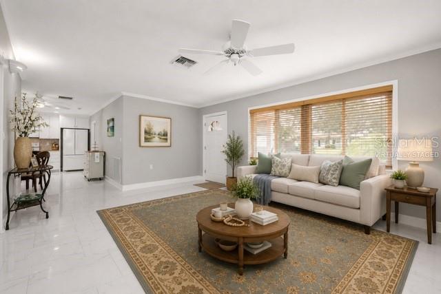 A living room features a beige sofa, a round wooden coffee table, and tile flooring — 328 BAYVIEW DRIVE NE, ST PETERSBURG, FL
