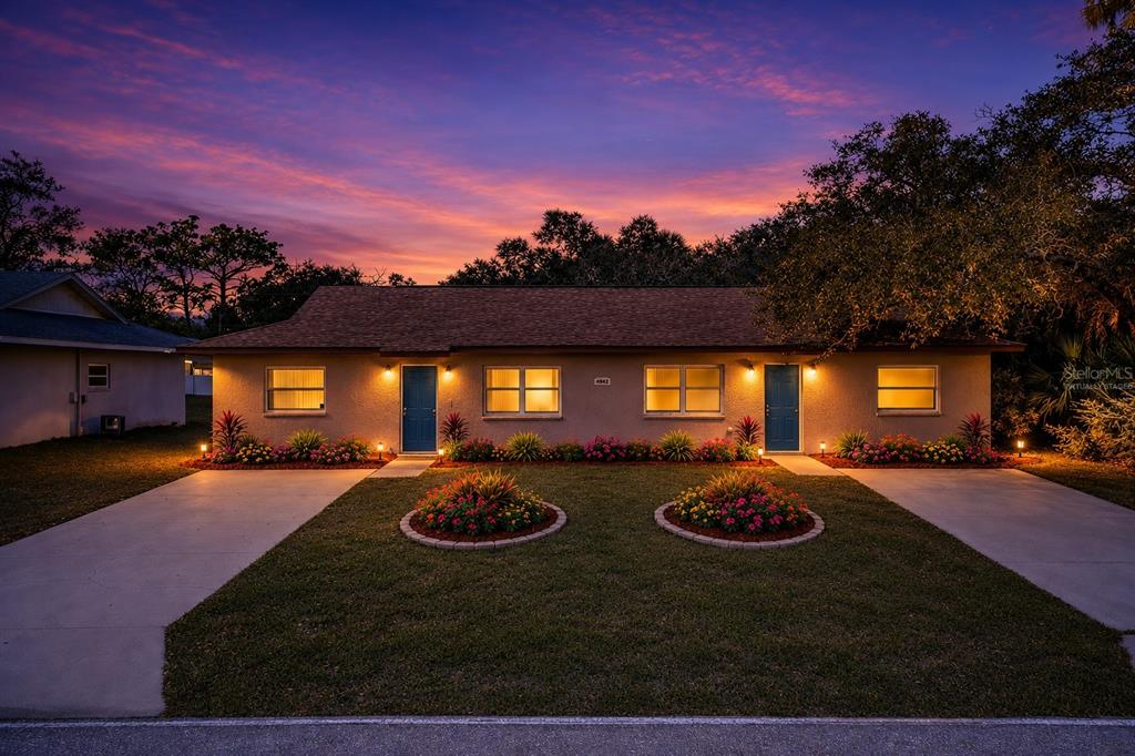 A single-story duplex with two blue front doors, concrete driveways, and landscaped flower beds — 2087 COMO STREET UNIT B, PORT CHARLOTTE, FL