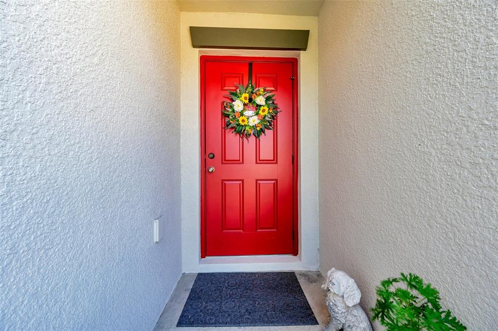 A bright red front door with a floral wreath sits in a recessed entryway — 1615 REDMOND BROOK LANE, RUSKIN, FL