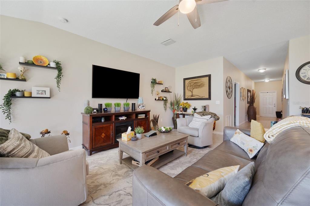 A living room features a television, a wooden media console, a coffee table, and seating — 1615 REDMOND BROOK LANE, RUSKIN, FL
