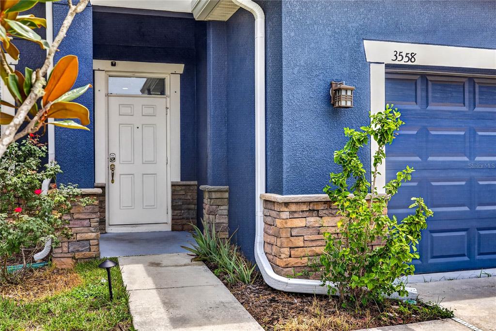 A blue house exterior features a white front door, stone accents, and a garage — 3558 BRACKNELL COURT, LAND O LAKES, FL