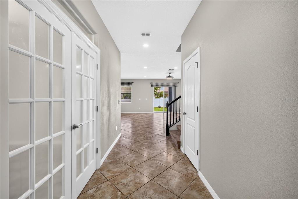 A tiled hallway leads past French doors and a staircase toward an open living area — 3558 BRACKNELL COURT, LAND O LAKES, FL