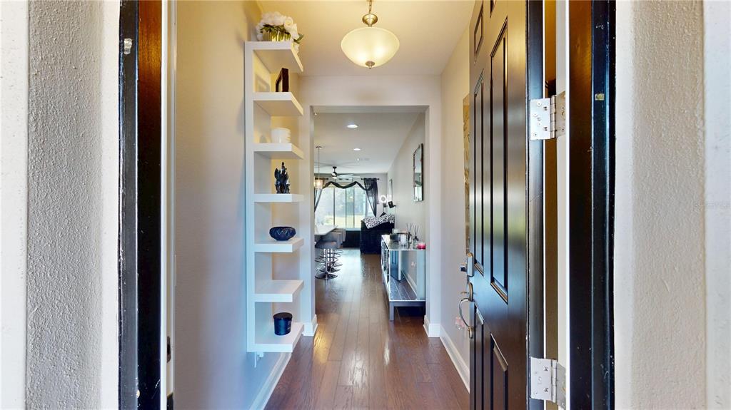 An entryway features a white wall-mounted shelving unit, hardwood flooring, and a black front door — 14223 PONDHAWK LANE, TAMPA, FL