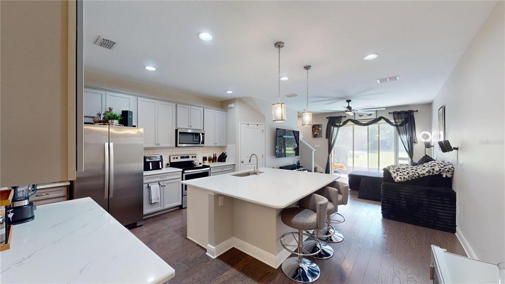 A kitchen with light gray cabinets, a white island, and stainless steel appliances — 14223 PONDHAWK LANE, TAMPA, FL