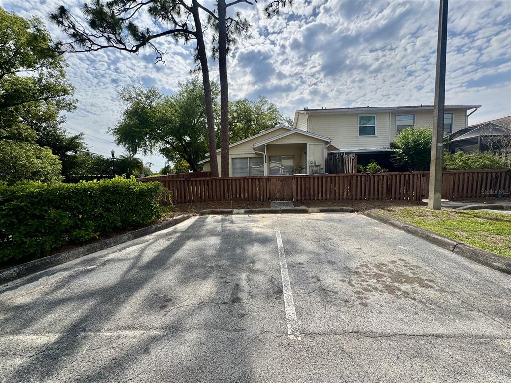 A two-story house with light siding stands behind a wooden fence and parking lot — 14607 PINE GLEN CIRCLE, LUTZ, FL