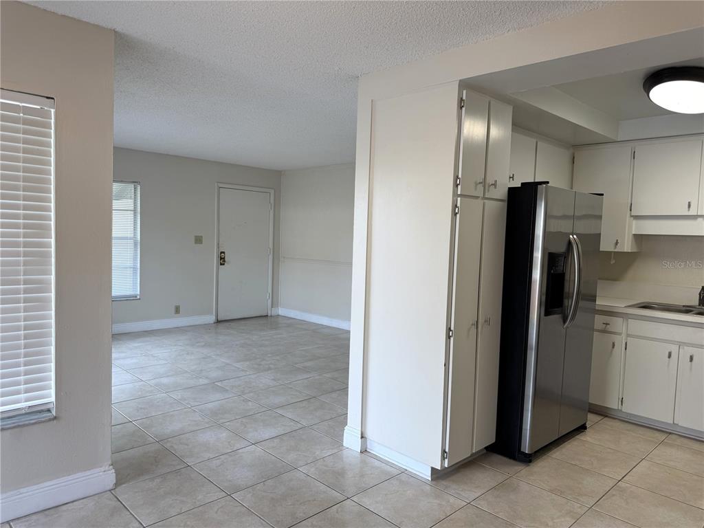 A kitchen with white cabinets and stainless steel appliances opens into a tiled living area — 14607 PINE GLEN CIRCLE, LUTZ, FL