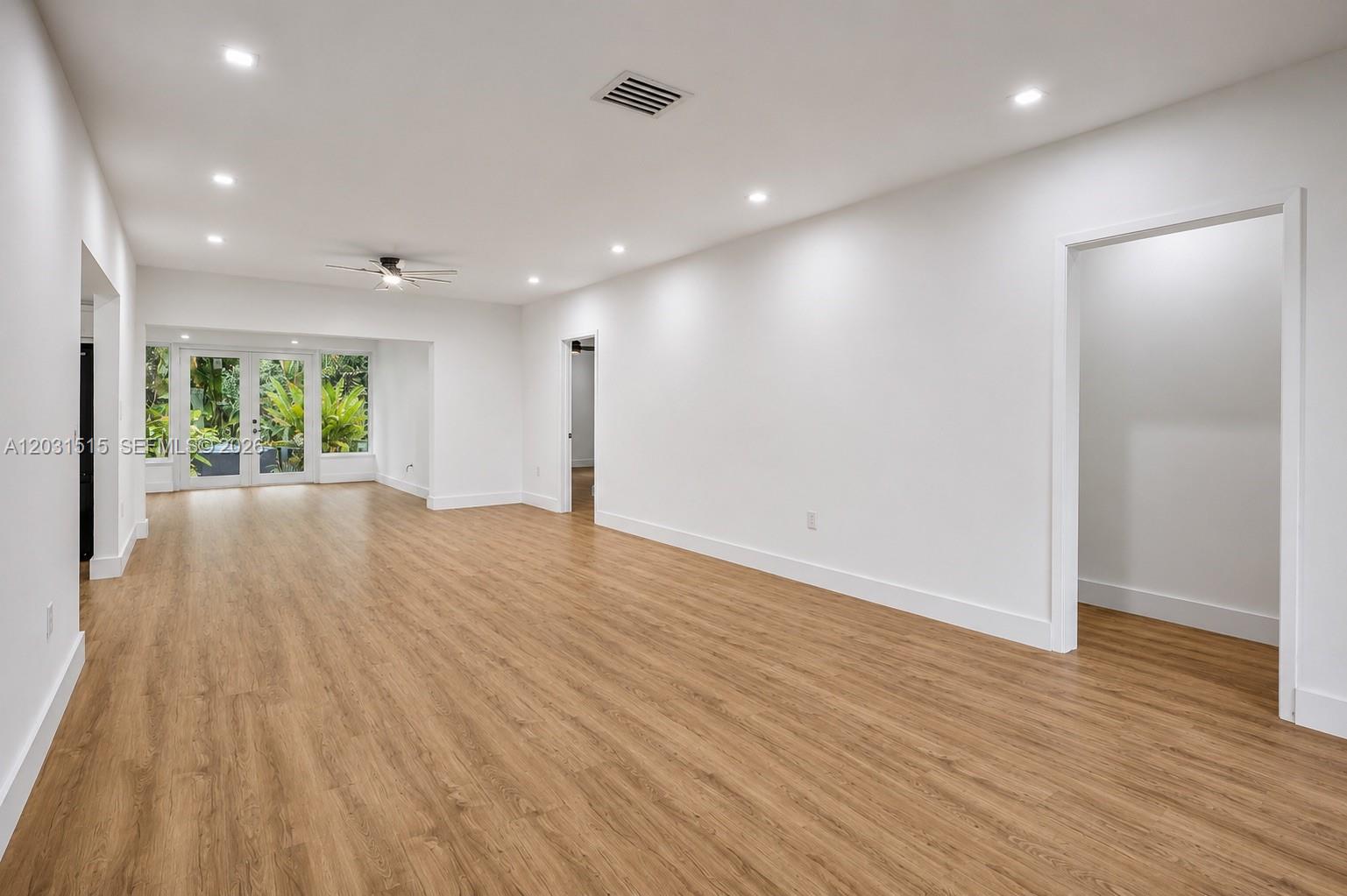 A spacious, empty room features white walls, recessed lighting, and light wood-look flooring — 8819 Dickens Ave, Surfside FL 33154, SURFSIDE, FL