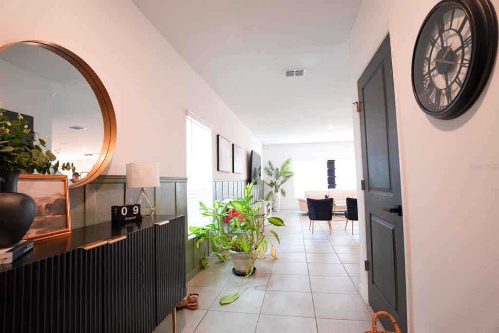 A hallway features a black console table, a round mirror, and green wainscoting on the wall — 112 BRINSMEAD ROAD, HAINES CITY, FL
