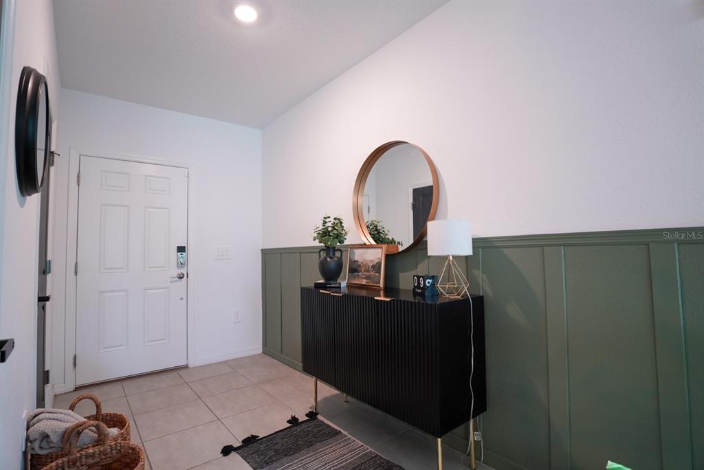 An entryway features a black console table, a round mirror, and green board-and-batten wall paneling — 112 BRINSMEAD ROAD, HAINES CITY, FL