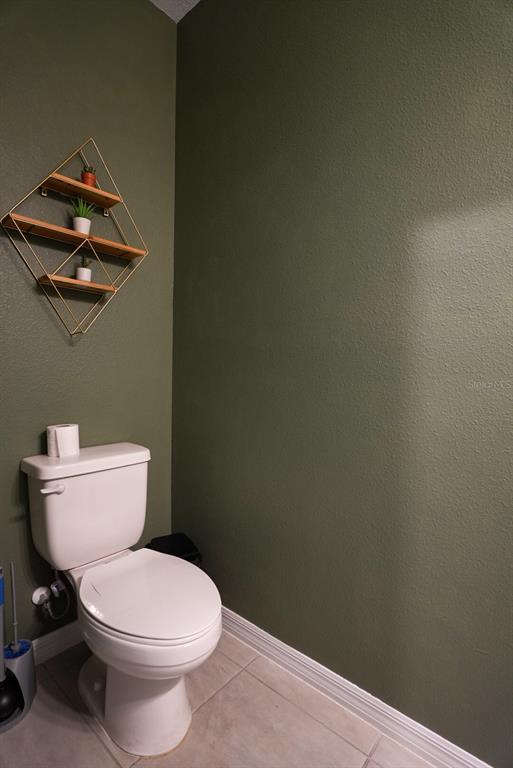 A bathroom features olive green walls, a white toilet, and a geometric wall-mounted shelf — 112 BRINSMEAD ROAD, HAINES CITY, FL