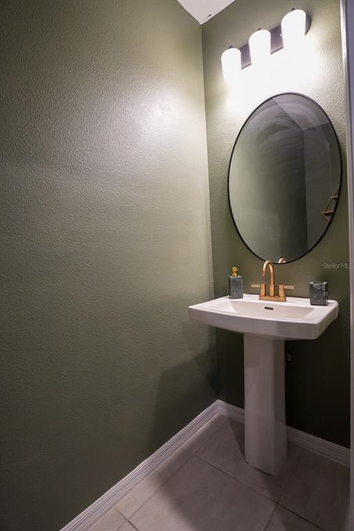 A powder room features a pedestal sink, gold faucet, oval mirror, and olive green walls — 112 BRINSMEAD ROAD, HAINES CITY, FL