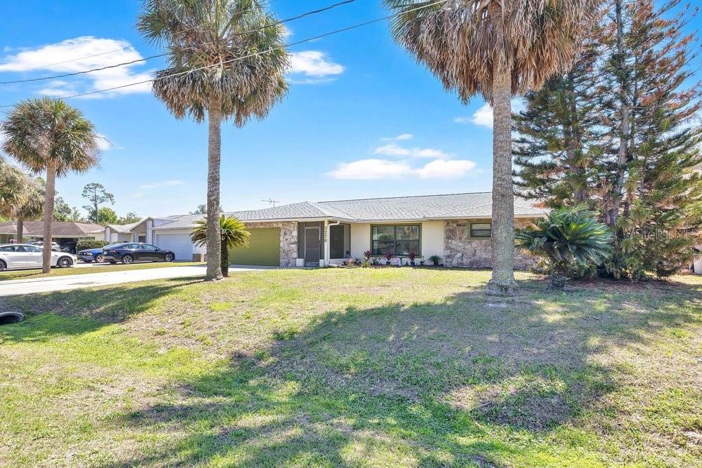 A single-story house with a stone facade, a green garage door, and palm trees — 3270 DEER LICK COURT, KISSIMMEE, FL