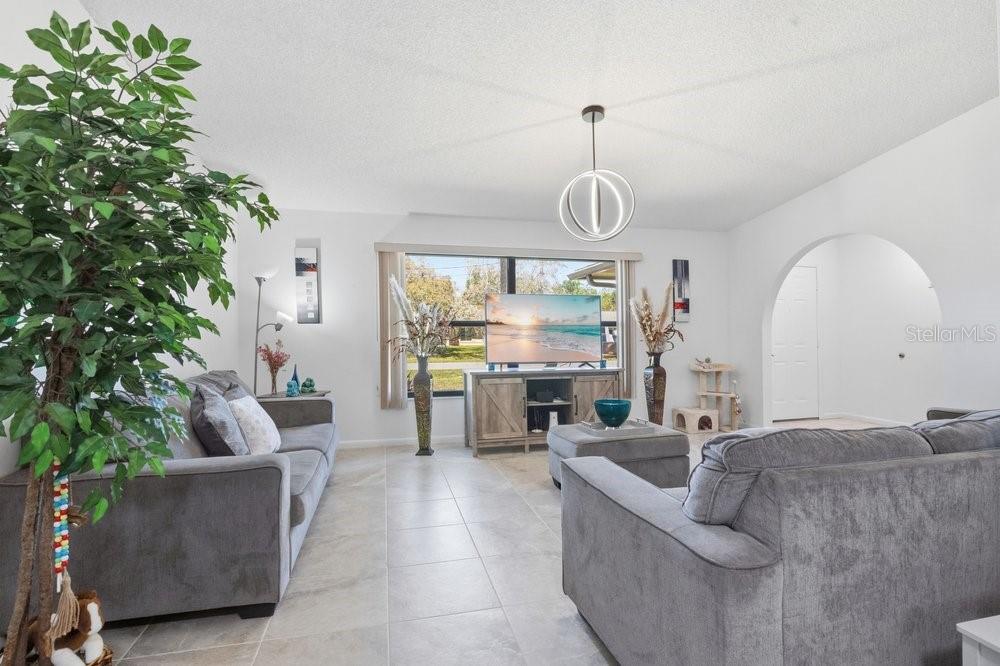 A living room with gray sofas, a television on a wooden stand, and tile flooring — 3270 DEER LICK COURT, KISSIMMEE, FL