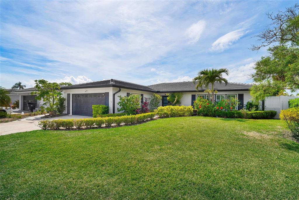 A single-story house with a dark garage door, white exterior, and a large front lawn — 3944 DORAL DRIVE, TAMPA, FL